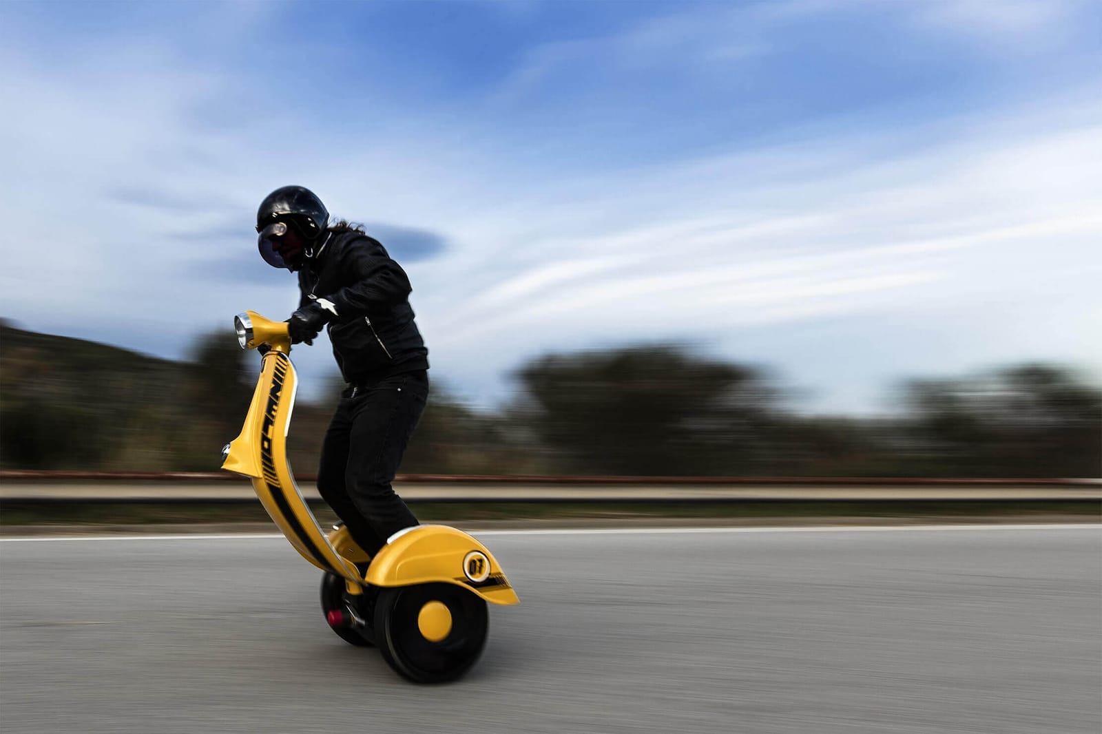Piloto con casco conduciendo un Z-Scooter amarillo en carretera